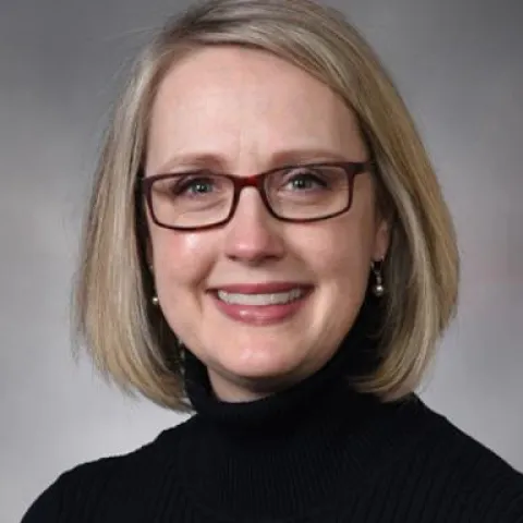 Emily Smith smiling against a grey backdrop. 