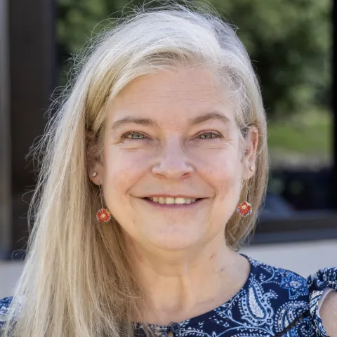 Barbara Martin wears a blue floral blouse while smiling for a picture. 