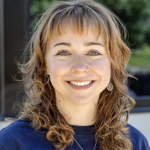 Merritt Manire wears a navy blue t-shirt while smiling for a photo. 