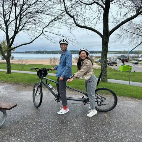 Jack and His Wife posing on a two person bike in a lovely park.