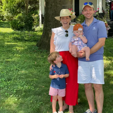 Family of four, with two young children, standing in their yard