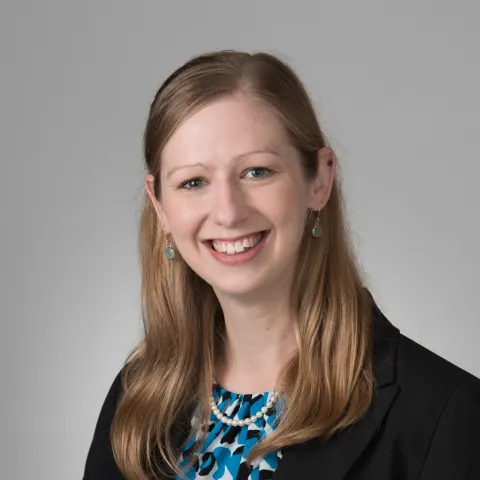 Headshot of Dr. Sarah Vick in a black overcoat and blue blouse