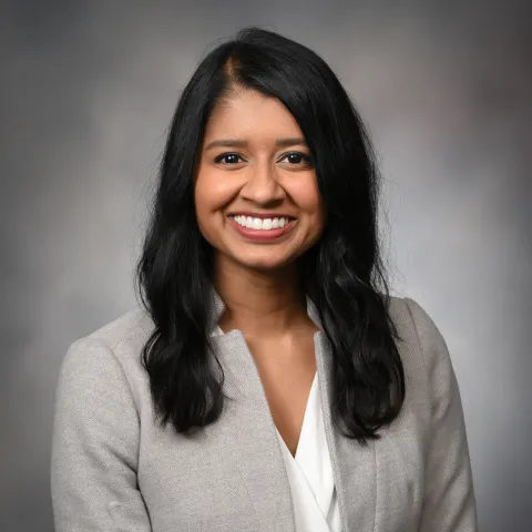 headshot of dr. micciche in gray suit, smiling