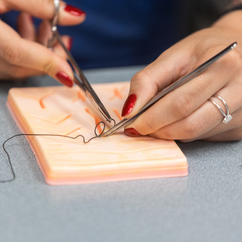 Close-up of hands working on suture