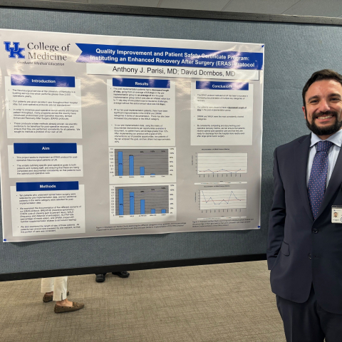 Resident stands in front of poster at GME poster presentation