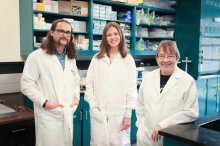 From left to right: Caleb Bailey, McKenna Green, and Linda van Eldik dressed in white coats in their lab.