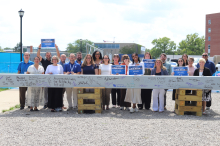  Faculty, staff, learners, and alumni signing a ceremonial beam