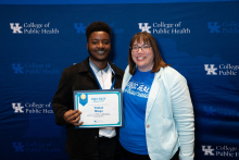 Young man standing with woman in white blazer holding an award