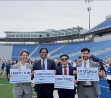 Smiling students at Kroger Field hold signs reading "I MATCHED!" with details of their medical residency matches.