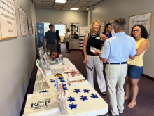 Two women and one man speak in a group in the hallway of the church, near a table of healthcare related swag and information.