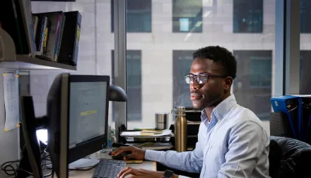 researcher siting at desk in front of desktop monitors