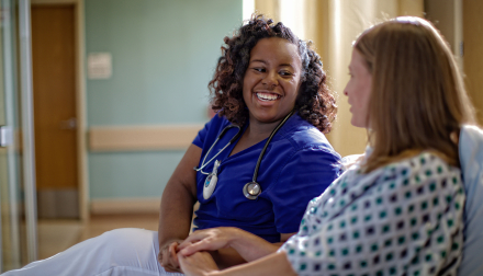 provider sitting beside patient in hospital bed