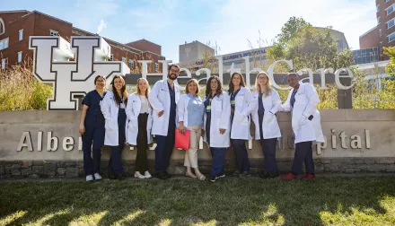 a group of uk college of medicine residents in scrubs and white coats stand in front of the uk chandler hospital