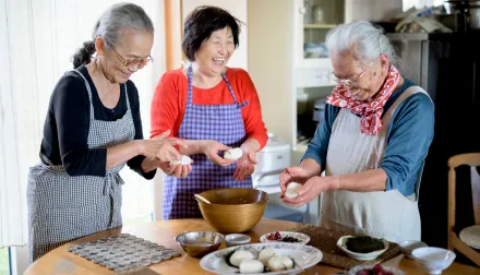 Elderly woman smiling, and cooking traditional dishes. 