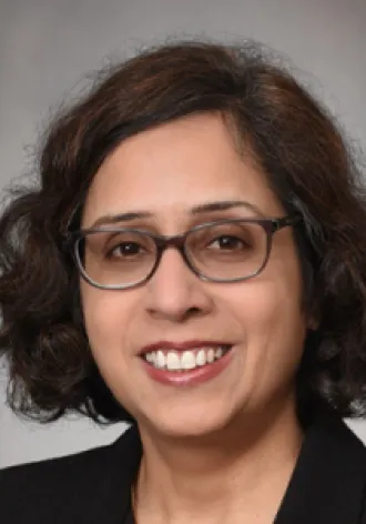 A photo of Dr. Chakravarti on a gray background, smiling for a headshot