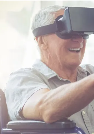 Elder man in wheelchair smiles while wearing a VR Headseat