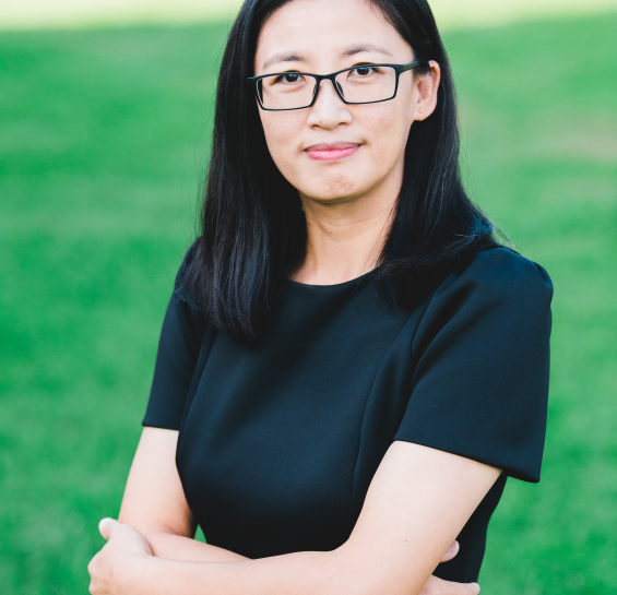 Dr. Zhang smiling at the camera in a black dress with blurred outdoor background