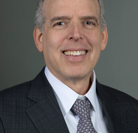 Dr. Himelhoch wearing a grey suit, white shirt and patterned tie smiling at the camera. 