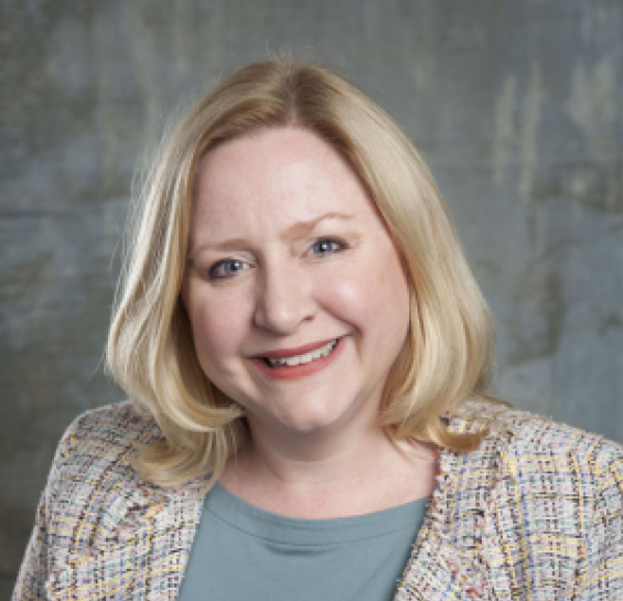 Woman in tan and blue plaid blazer, blue blouse, and shoulder length blonde hair