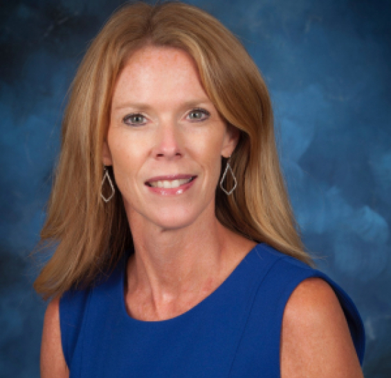 Woman in blue dress with shoulder length red hair and earrings