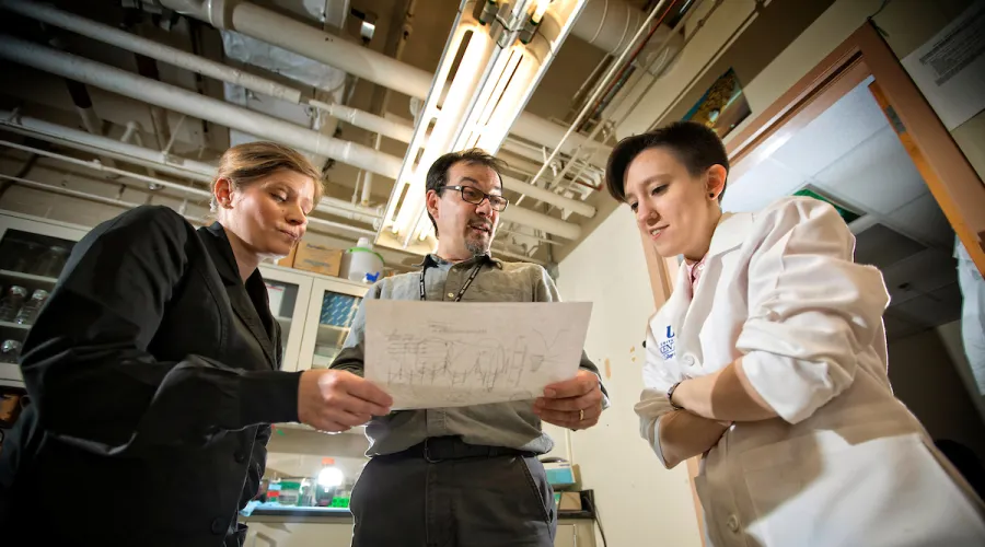 Three scientists looking at data on a page.