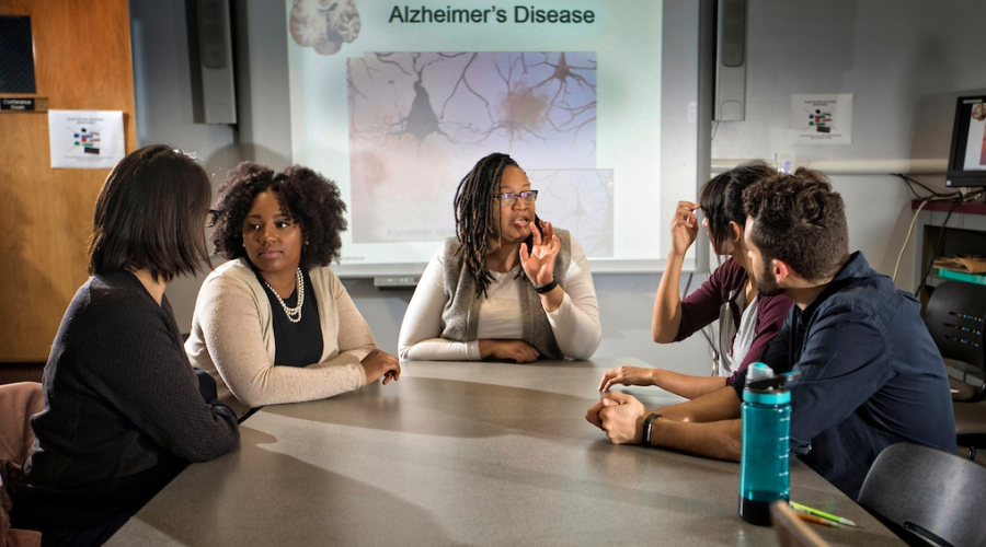 Teacher and students around a table, discussing Alzheimer's.
