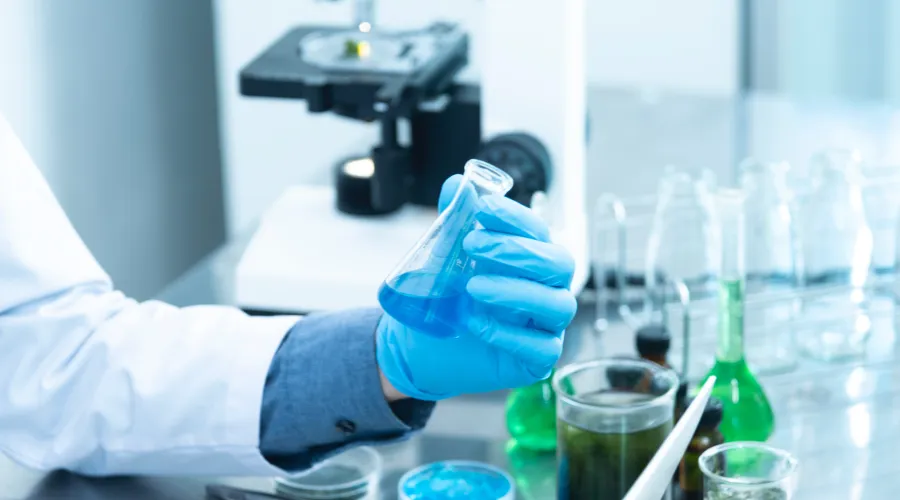 Gloved hand holding a beaker in the lab.