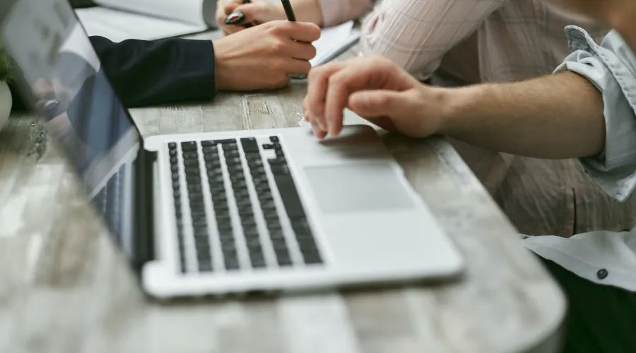 Individuals using laptops at a conference table.