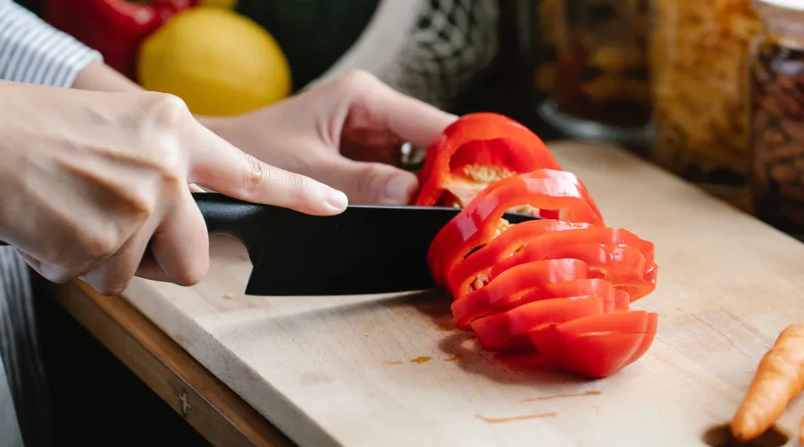 Close up of someone cutting tomatoes on a cutting board.