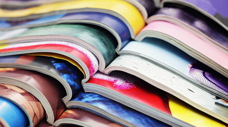Multi-colored magazines or books open halfway and placed on top of each other