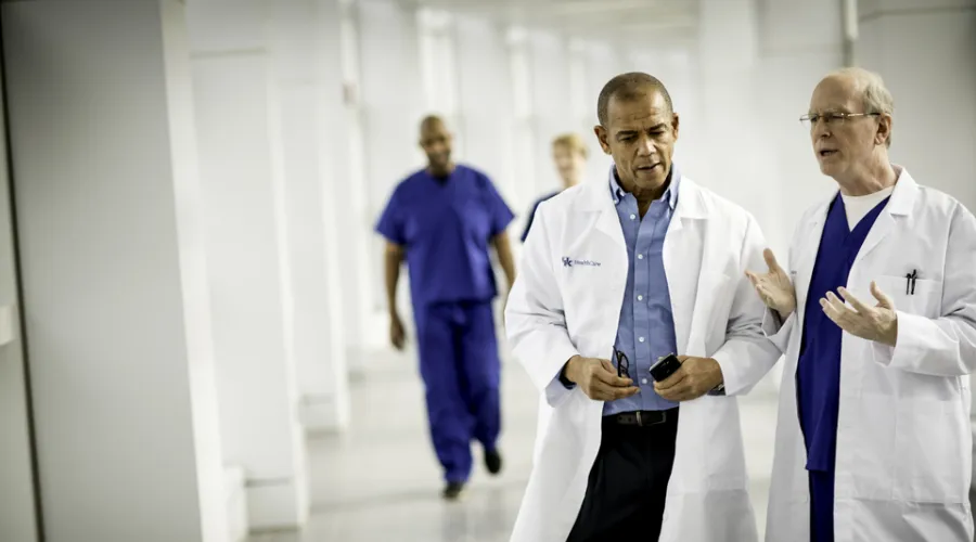 Two doctors conversing, walking through UK hospital