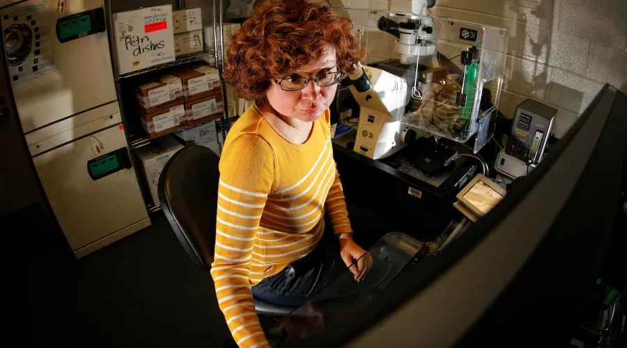 researcher in front of a computer; laboratory equipment in background