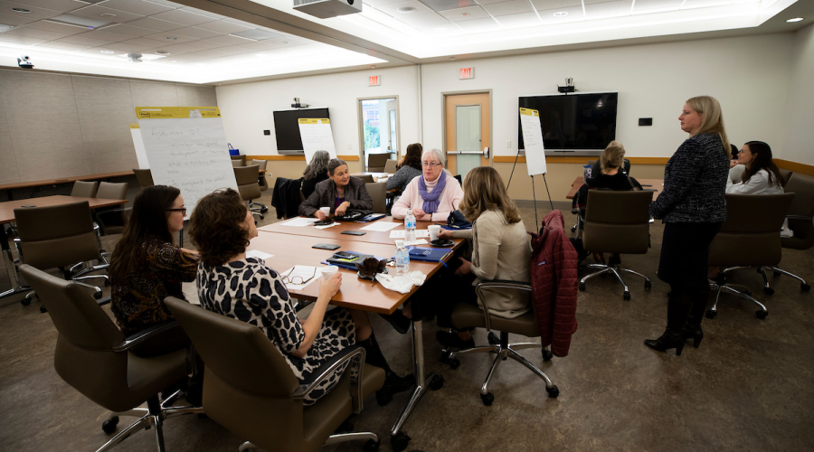 group of people sitting around a conference room table with a white paper flip board to the side