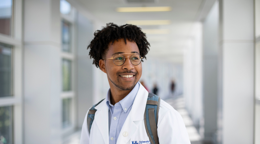 person in a white medical coat smiling and looking to the side
