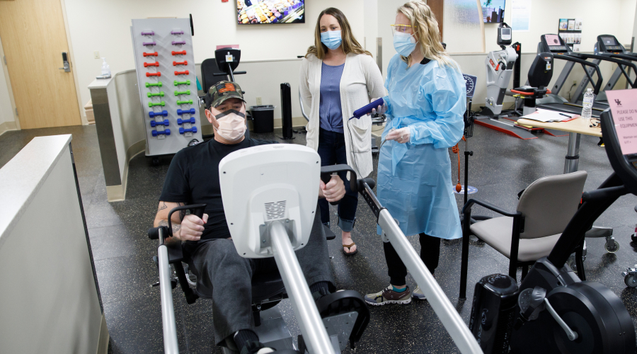 patient using exercise equipment with physical therapist