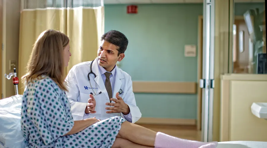 doctor consulting with patient; both patient and doctor sitting on bed