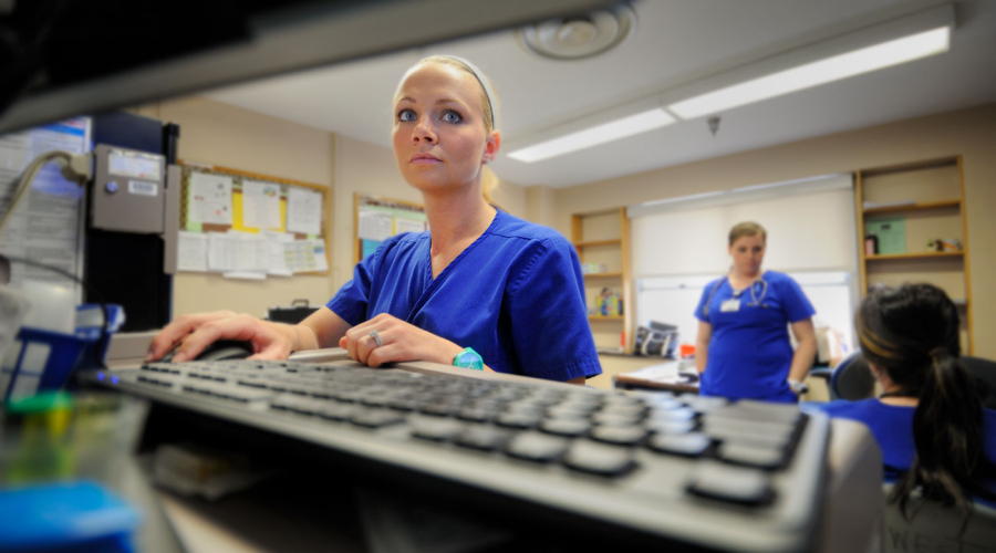 nurse standing in front of a computer and keyboard