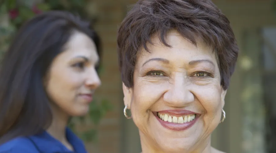 person smiling at the camera; second person behind
