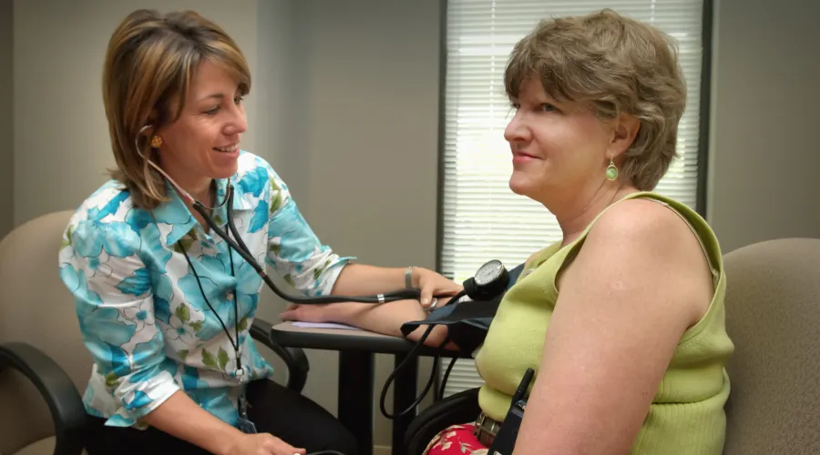 doctor is taking patient's blood pressure with cuff