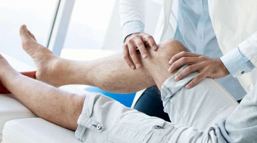 Doctor assisting patient with physical therapy on their knee