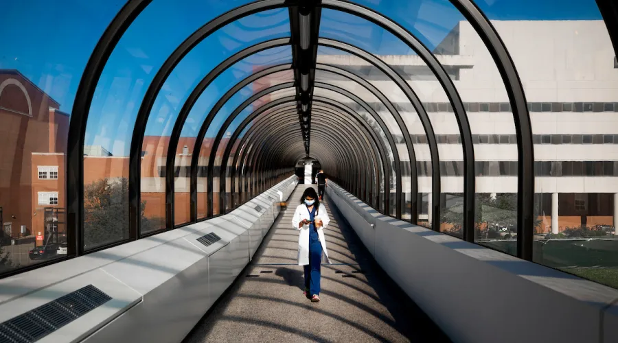 medical resident walking through the walkway from Chandler Medical to the parking structure