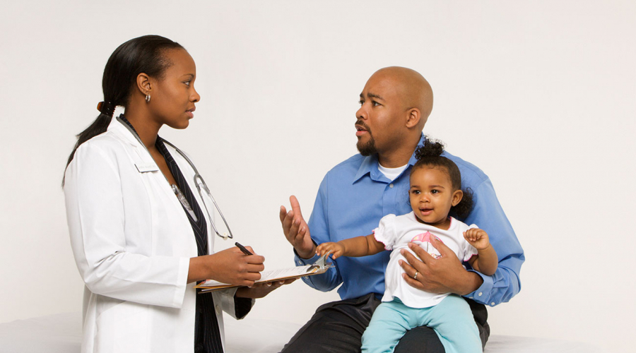 parent holding small child while speaking with doctor