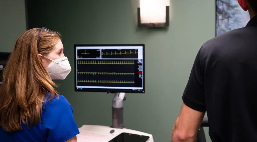 provider monitoring a patient with a results screen in background