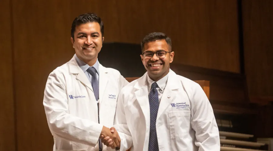 one alumni and one student shaking hands during white coat ceremony