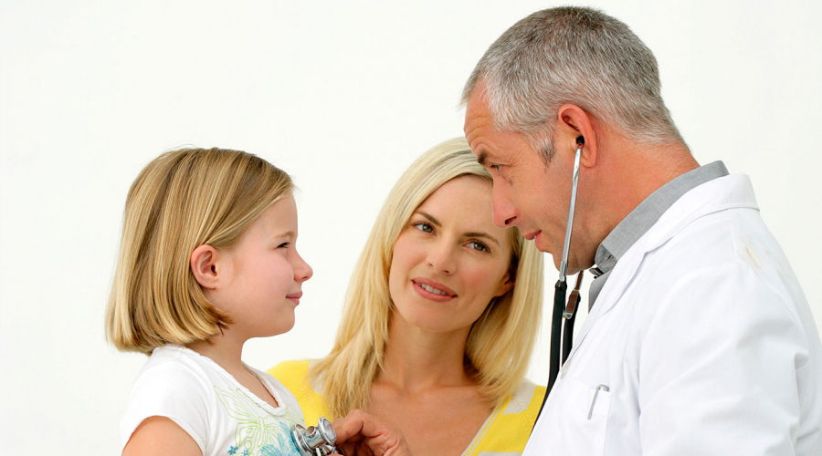 doctor listening to child's heart with stethoscope; parent standing in between
