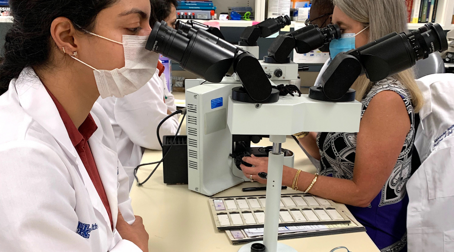 Residents using microscopes participating in cytology sign-out.