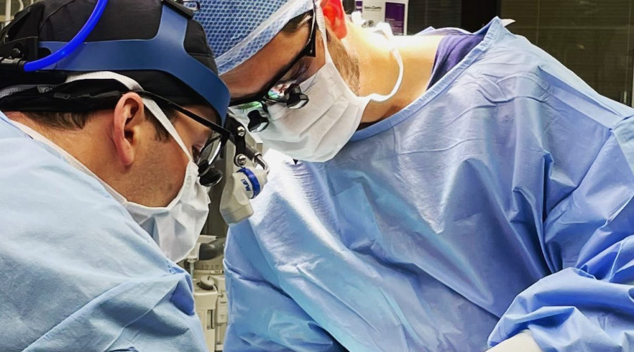 two surgeons using a tool in the nose of a patient in an operating room.