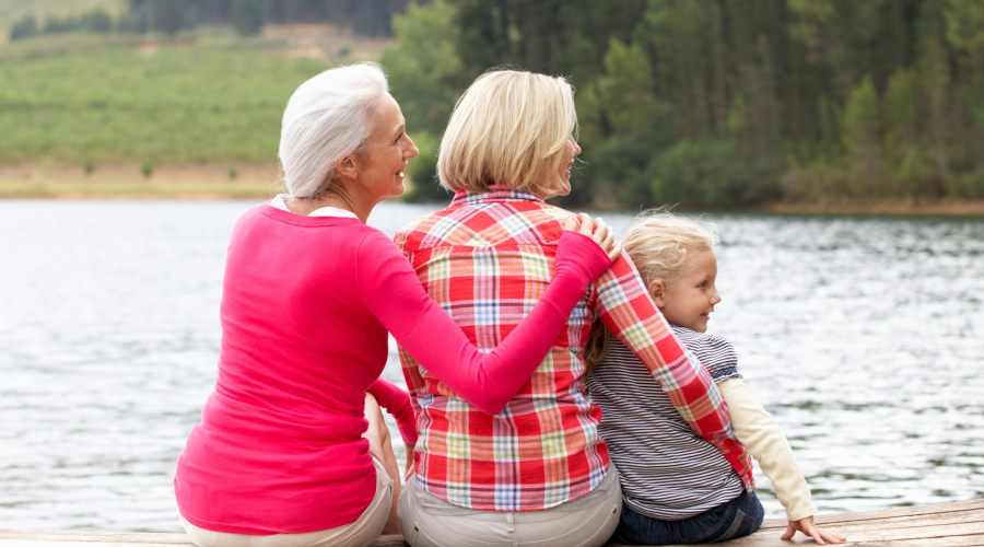 three generations of females sitting by a lake
