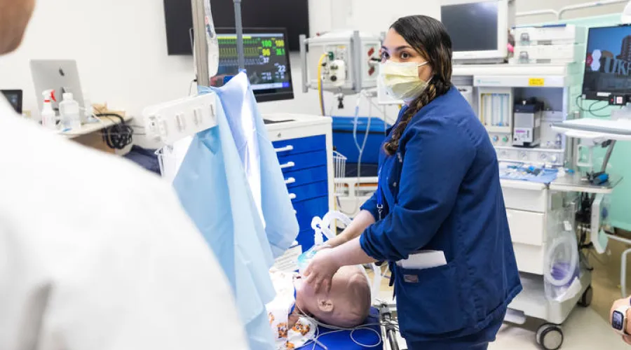 Anesthesiologist resident or fellow in simulation training with human mannequin on table