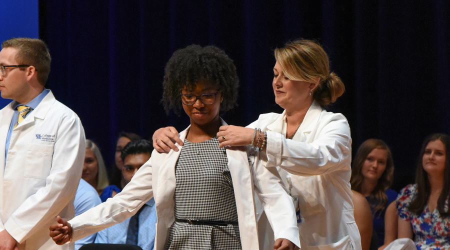 A student receiving their white coat on stage